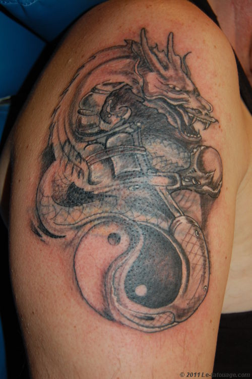Tatuaggio sul deltoide il dragone disegnato in stile Yin-Yang