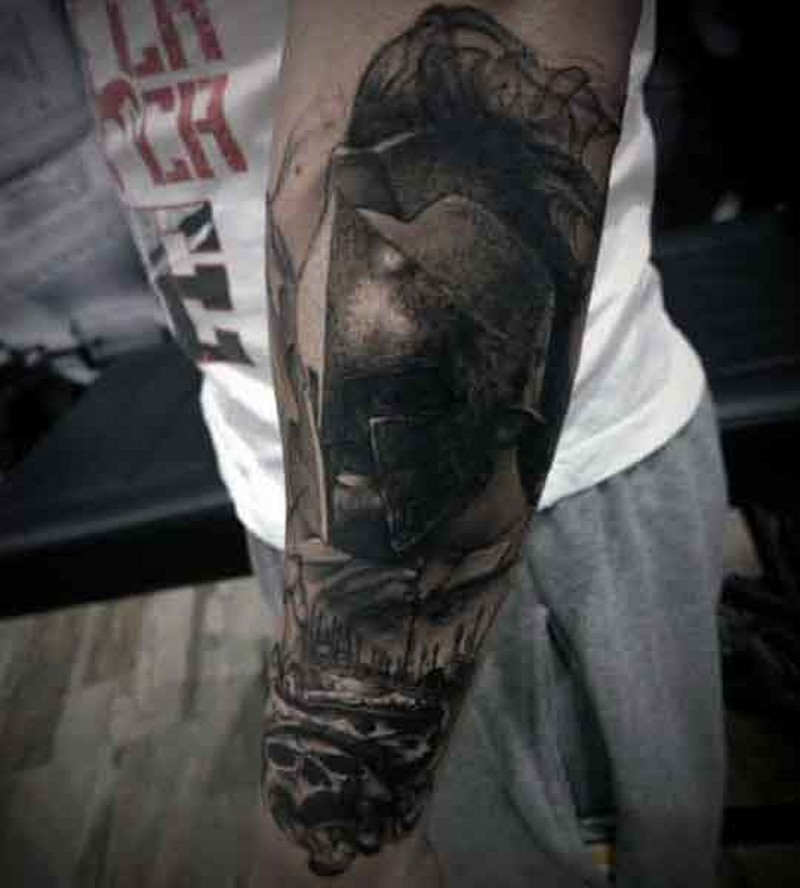 Dramatic black ink Spartan warrior tattoo on forearm combined with skulls