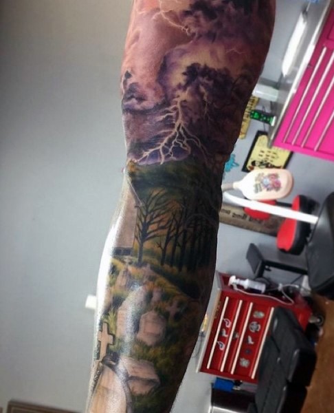 Dramatic colored sleeve tattoo of cemetery with dark sky and lightning