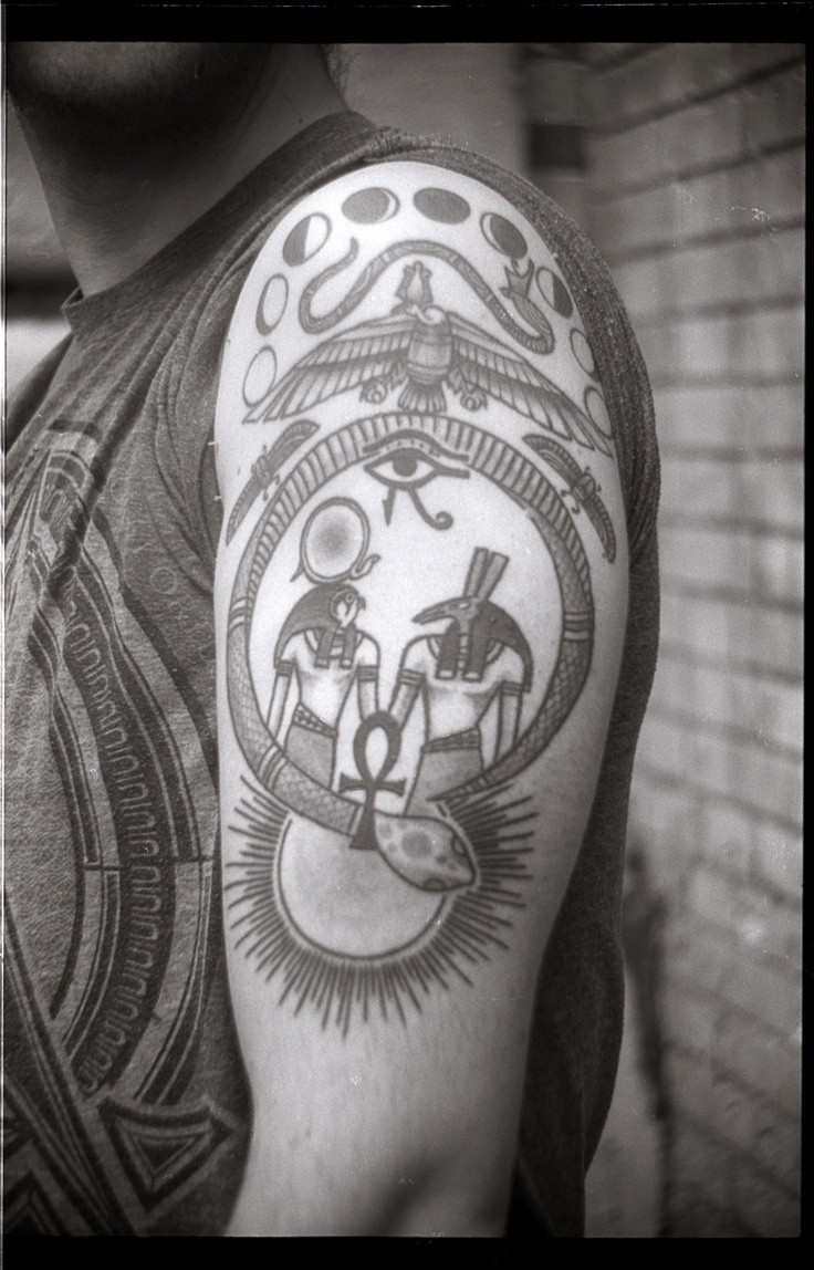 Tatuaje en el brazo de deidades egipcias y símbolos de poder.