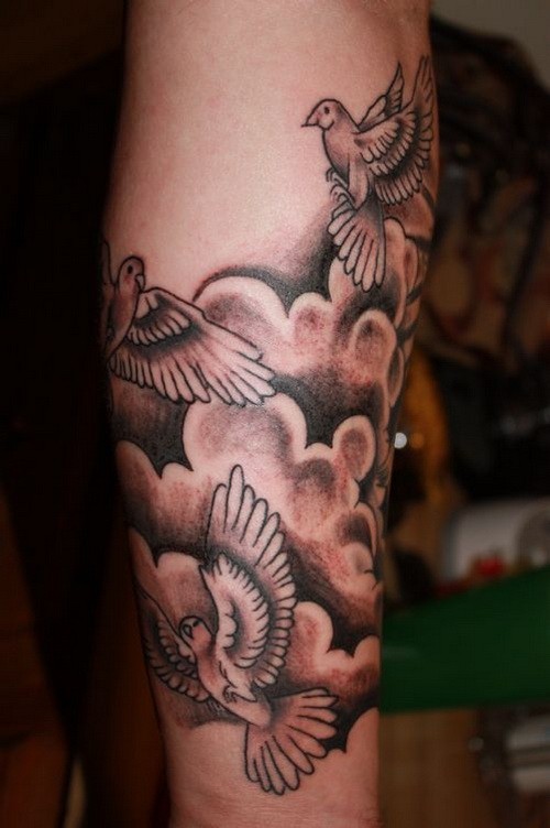 Elegantes graues Tattoo von fliegenden in Wolken Vögeln in Tusche als Ärmel gestaltet am Unterarm