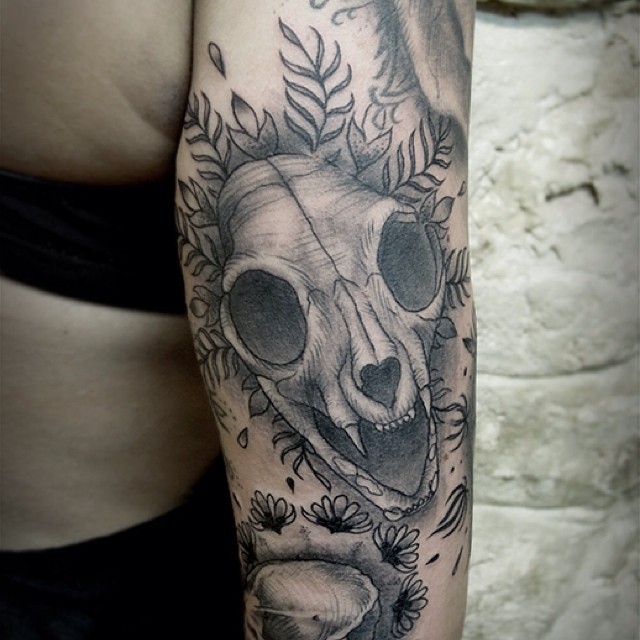 Tatuaje negro blanco en el brazo,
 cráneo de animal y maleza