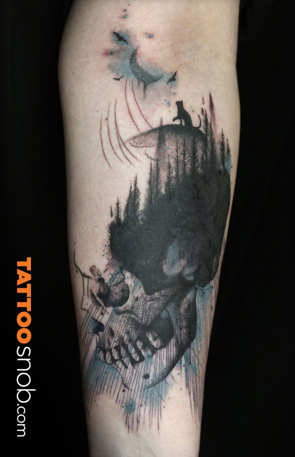 Engraving style black and white forearm tattoo of big skull stylized with forest and moon