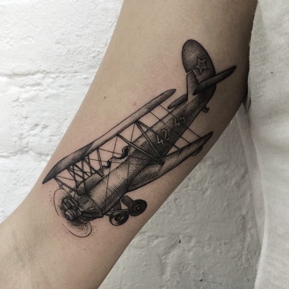 Engraving style black ink arm tattoo of vintage plane