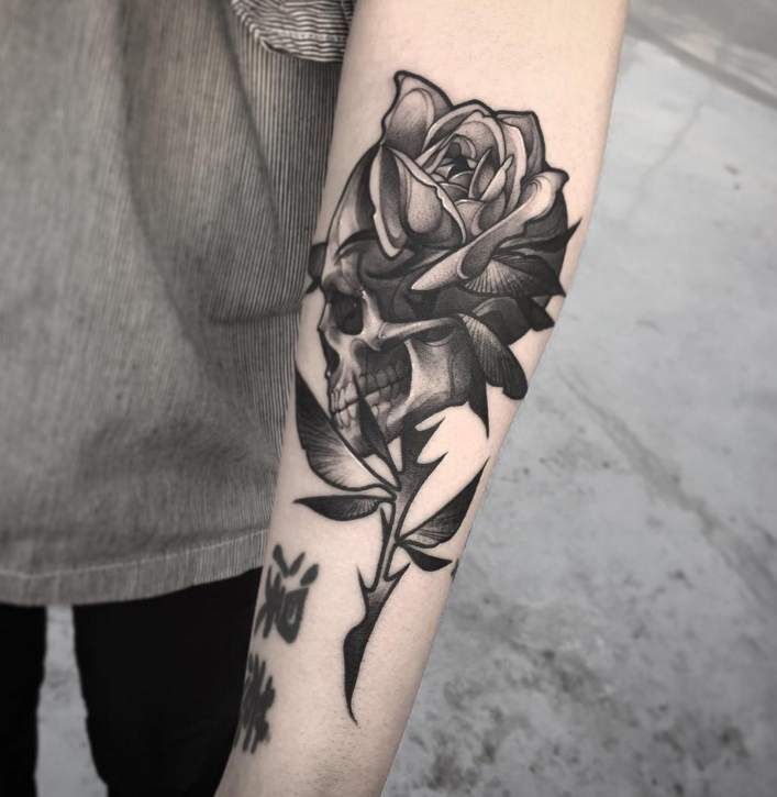 Engraving style black ink forearm tattoo of big rose with human skull