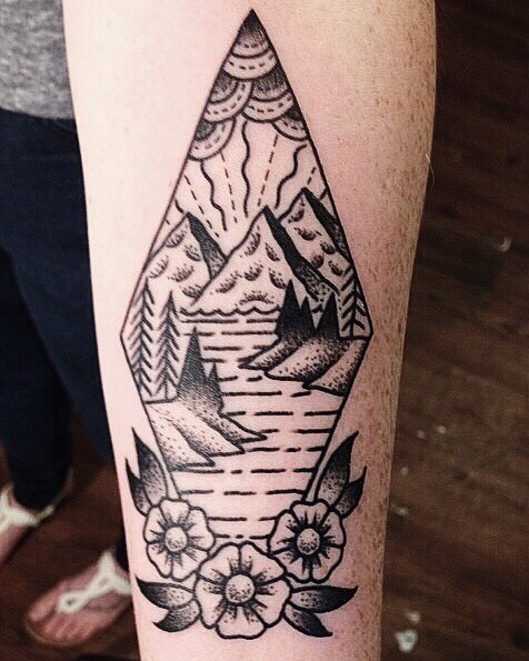 Tatuaje negro blanco en el antebrazo, montañas con río en rombo decorado con flores