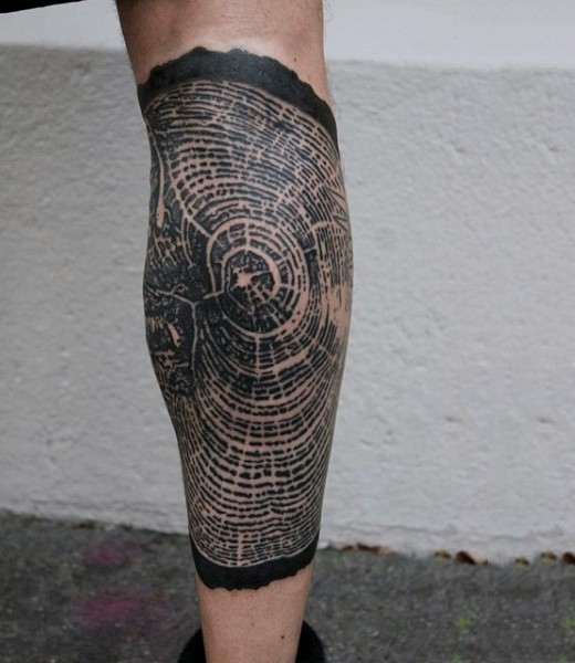 Engraving style black ink leg tattoo of crossed section of the tree