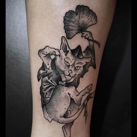 Engraving style black ink leg tattoo of evil cat with leaves