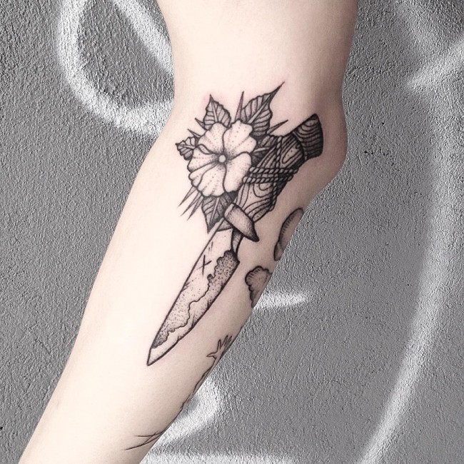 Engraving style black ink old knife with flower tattoo on forearm