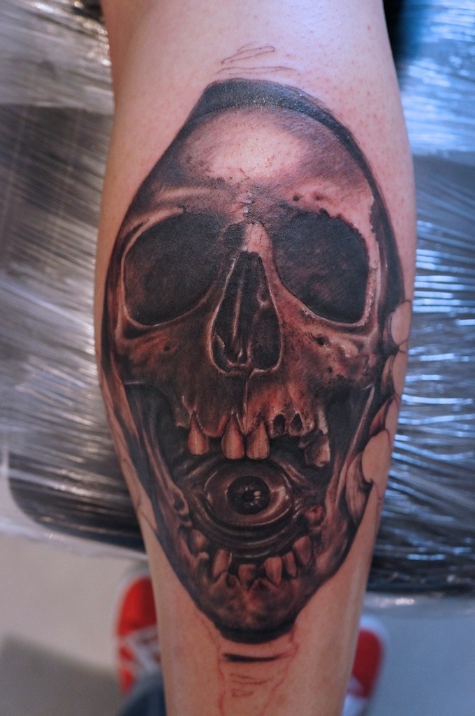 Tatuaje en el brazo, cráneo con un ojo en la boca