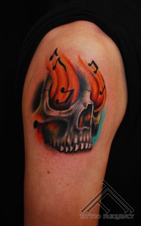 fantastico dipinto piccolo colorato cranio musicale con fiamme tatuaggio su spalla
