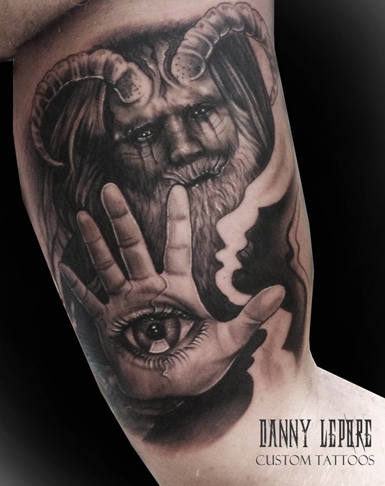 Fantasy style colored biceps tattoo of devil with human eye on hand