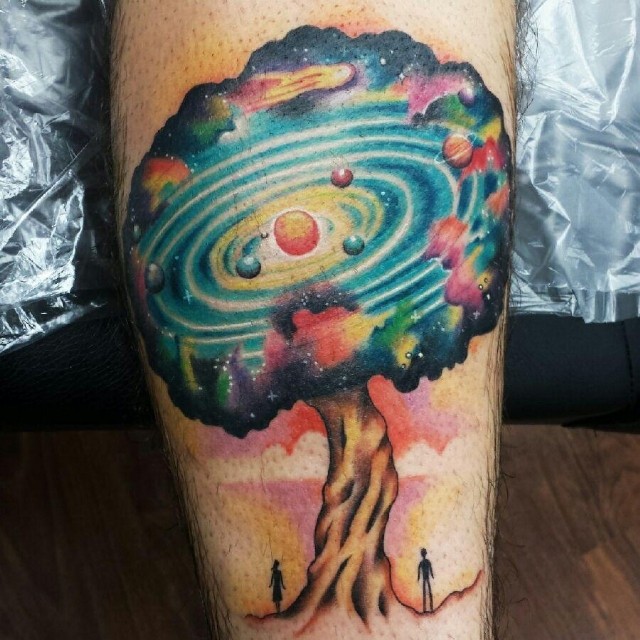 Fantasy style colored leg tattoo of big tree with solar system