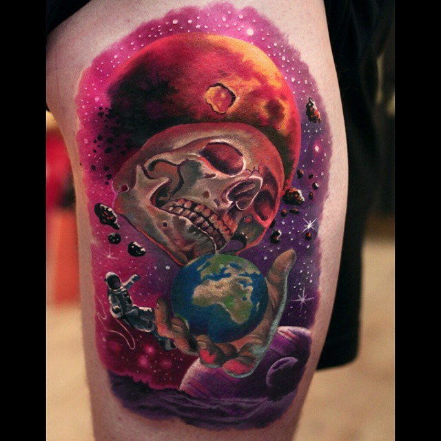 Fantasy style colored shoulder tattoo of human skull with planet on thigh