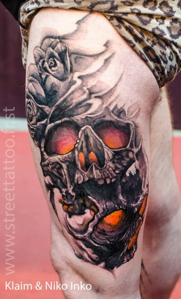 Fantasy style colored thigh tattoo of big human skull with roses