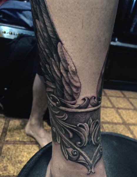 Fantasy world like black ink crown with wings tattoo on ankle