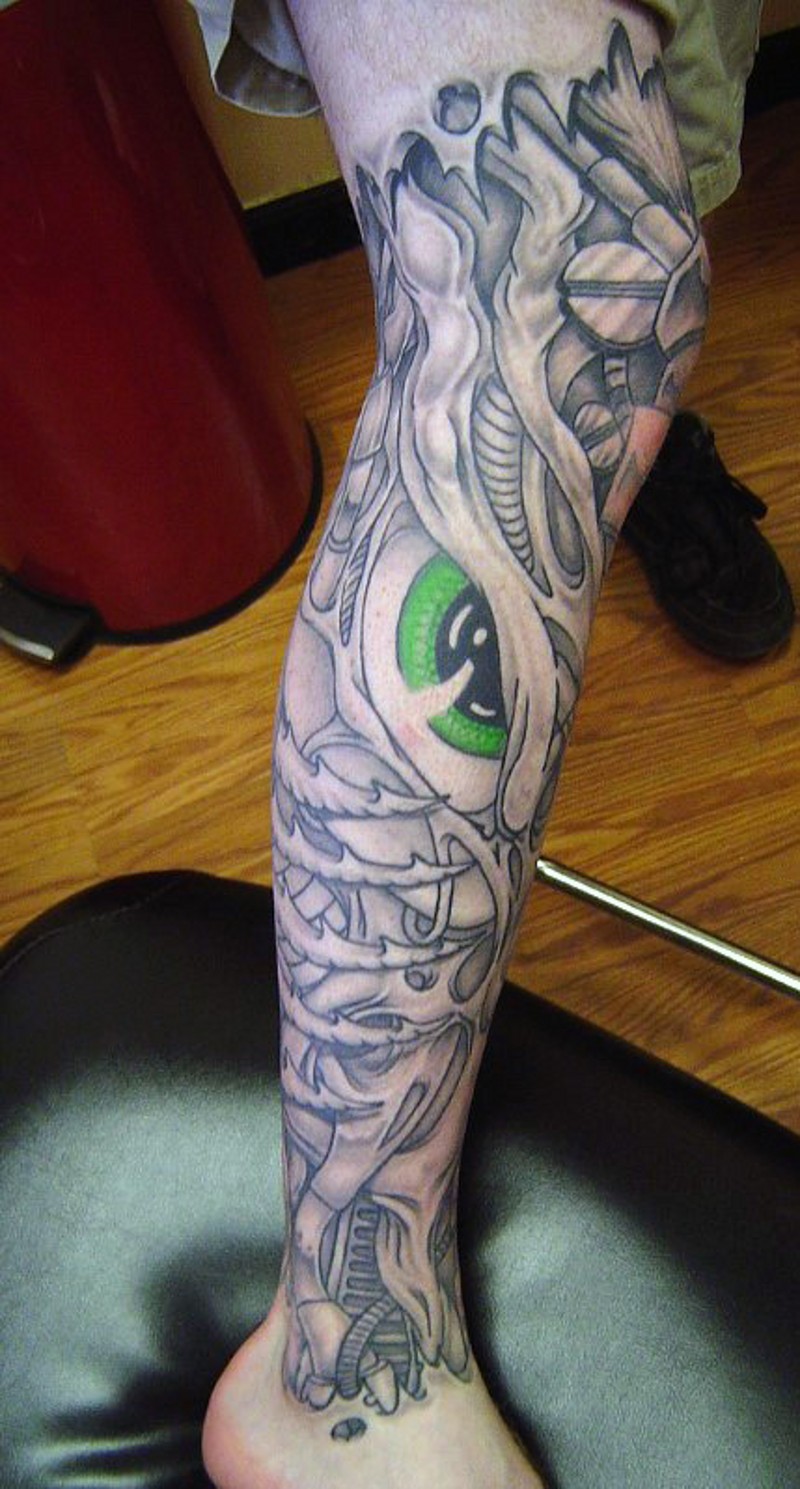 Fantasy world like evil monster with green eye tattoo on leg