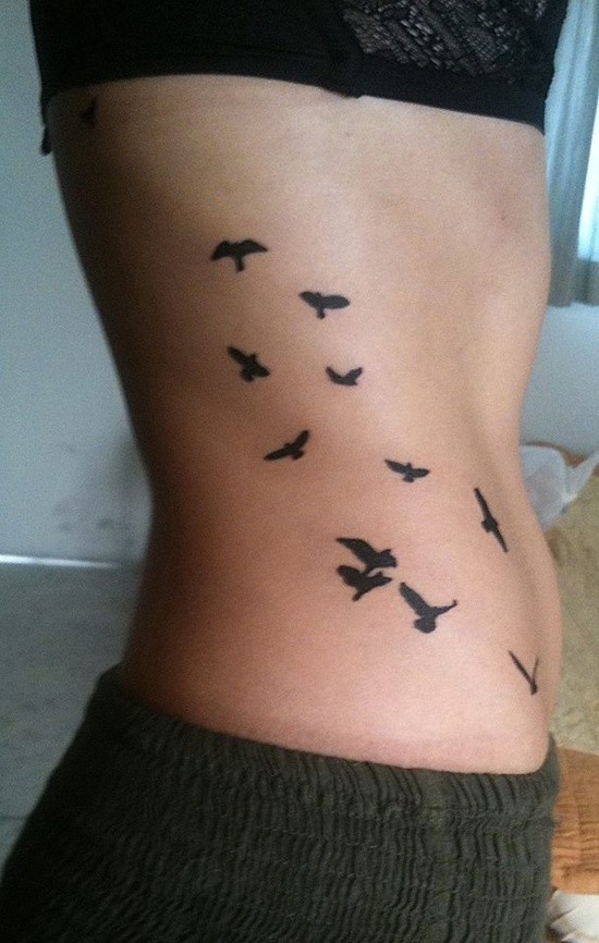 Tatuaje en el costado, bandada de aves negras diminutas