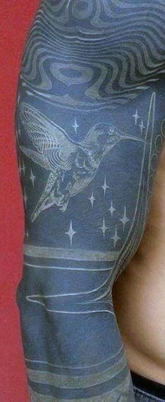 Tatuaje en el brazo, colibrí lindo de tinta blanca en el fondo negro