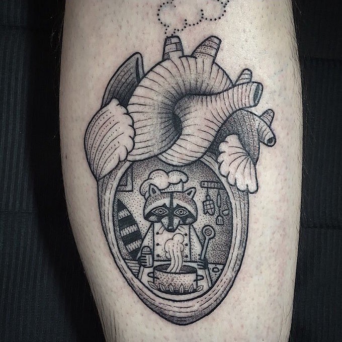 Tatuaje en la pierna, corazón humano con mapache cocinando en él