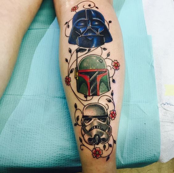 Tatuaje en la pierna, tres cascos de héroes de la guerra de las galaxias con flores lindas diminutas