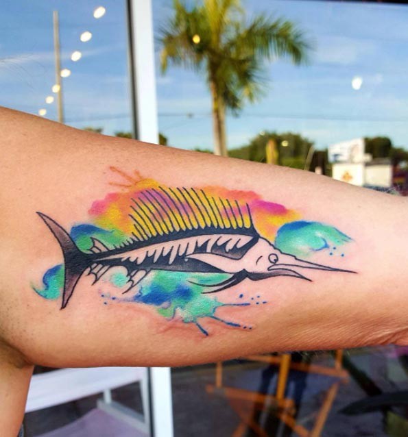 Funny cartoon like swordfish decorated with colored paint drips biceps tattoo