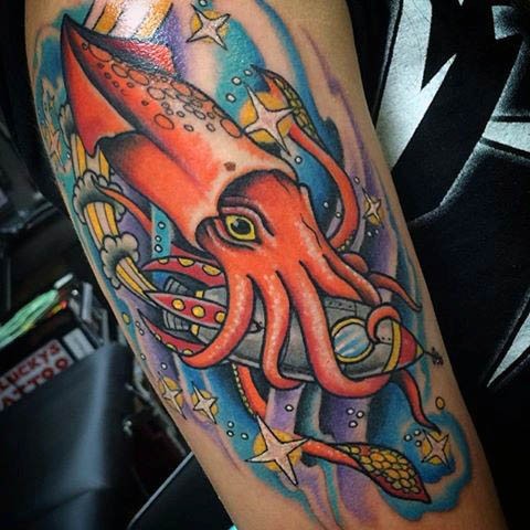 Funny designed and colored big squid in space with rocket tattoo on sleeve