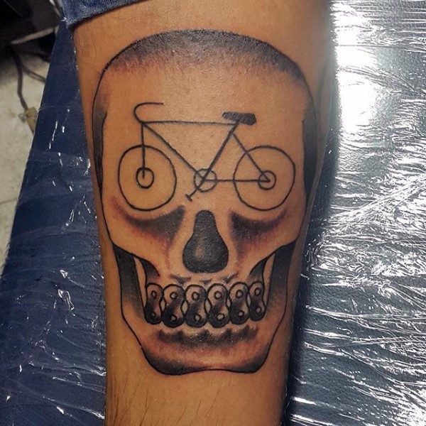 Tatuaje en el antebrazo, cráneo divertido con bicicleta en la frente