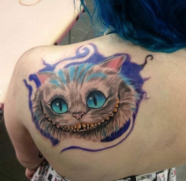 Funny fairy tale smiling Cheshire cat colored detailed upper back tattoo with violet paint shadow