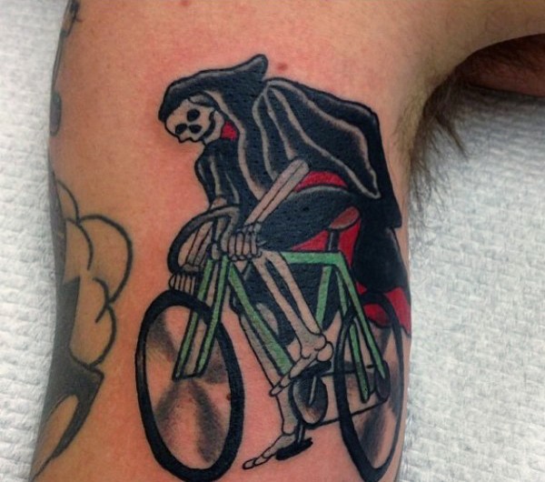 Funny grim reaper on cycle colored tattoo on biceps