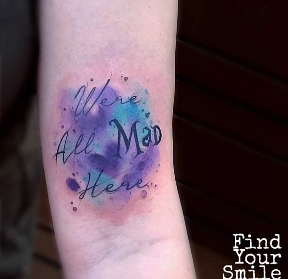 Funny lettering and violet blue paint drips tattoo on arm in watercolor style
