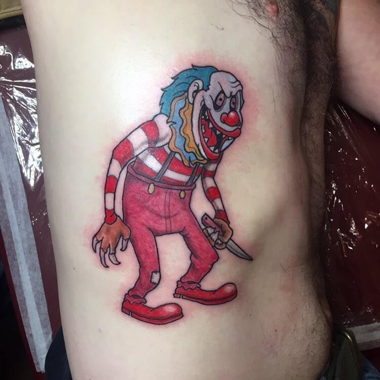 Funny looking cartoon style colored side tattoo of maniac clown with knife