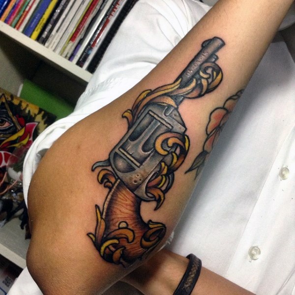 Funny looking colored forearm tattoo of old revolver
