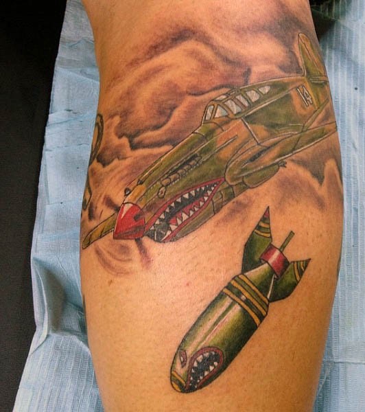 Funny looking colored leg tattoo of bomber plane and big bomb