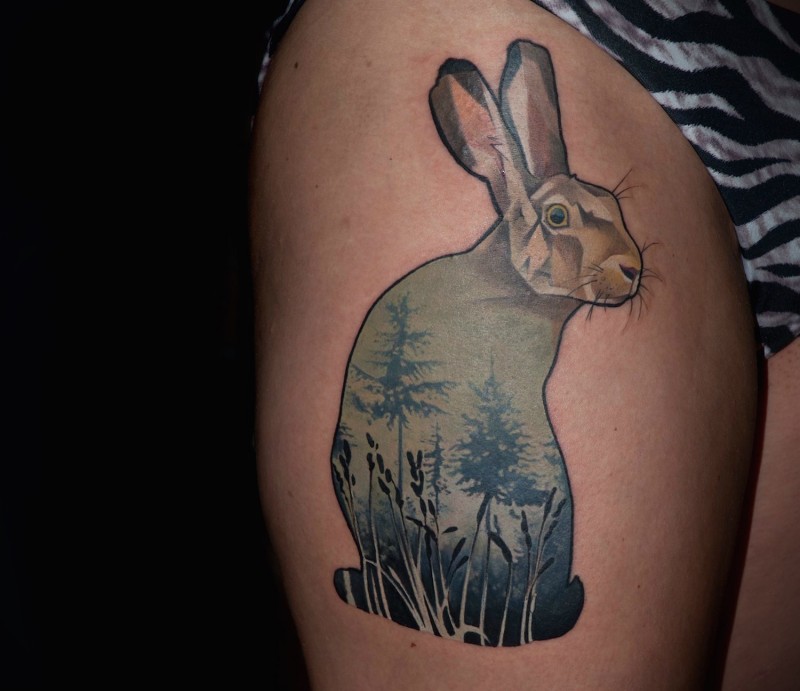 Funny looking colored thigh tattoo of rabbit stylized with forest