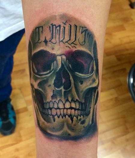 Tatuaje en el antebrazo, cráneo con frase en la frente