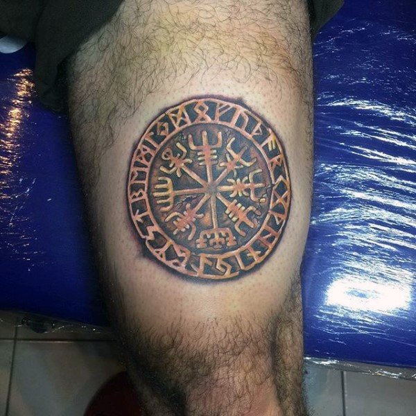 Golden like colored thigh tattoo of ancient emblem