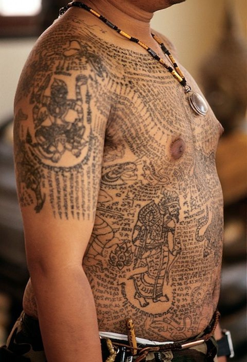 Gorgeous black ink detailed whole body tattoo of various tribal paintings and lettering