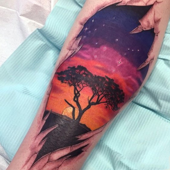 Wunderschöner farbiger einsamer Baum mit Sonnenuntergang Tattoo am Bein