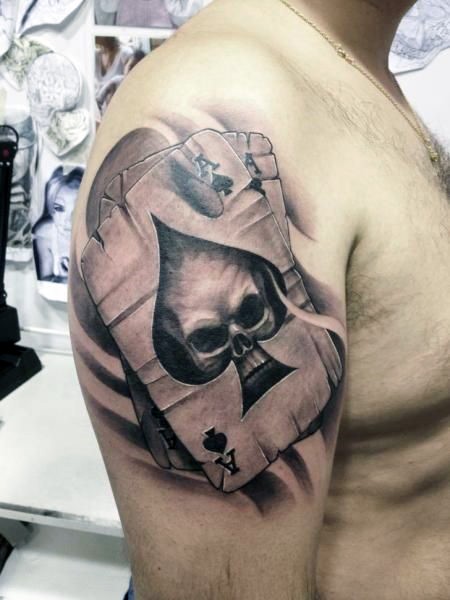 Tatuaje en el brazo, naipes con cráneo en el simbolo pica