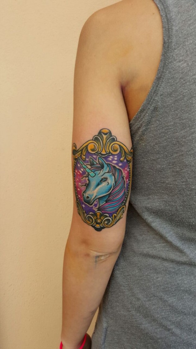Gorgeous fairy tale colored unicorn in old style frame tattoo on biceps