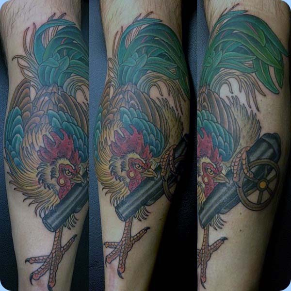 Herrlicher mehrfarbiger Hahn mit mittelalterlicher Kanone Tattoo am Arm