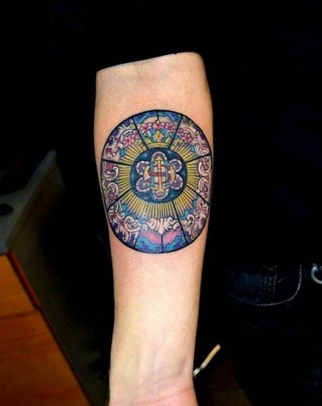 Gorgeous painted and colored circle shaped tattoo on forearm stylized with flowers