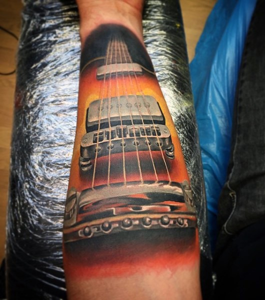 Gorgeous very detailed colored guitar tattoo on arm