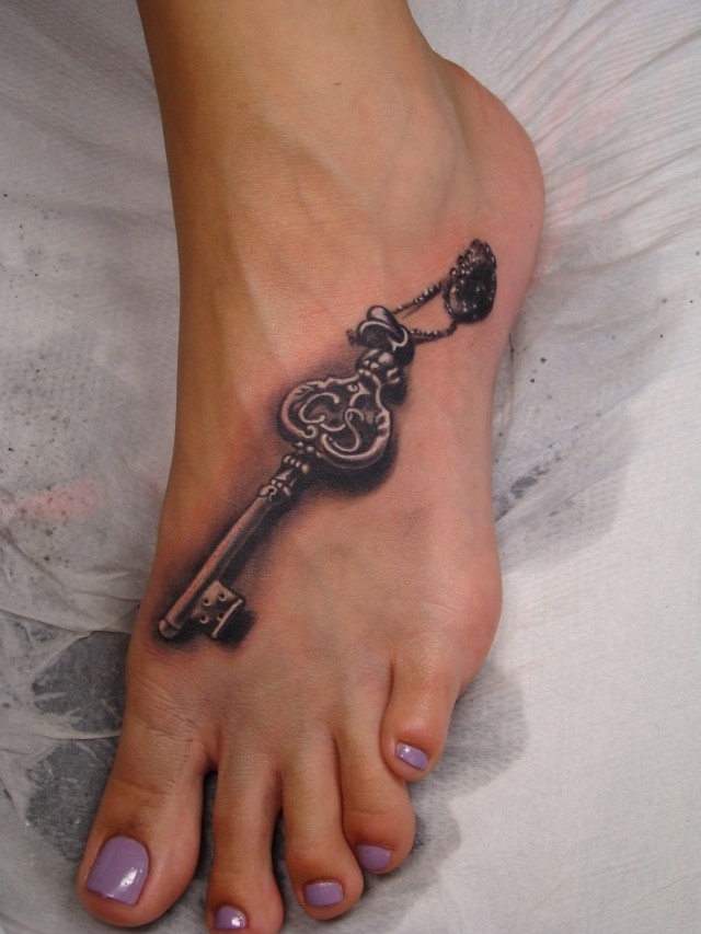 Tattoo von grauem 3D Schlüssel in Tusche auf dem Fuß für Frauen