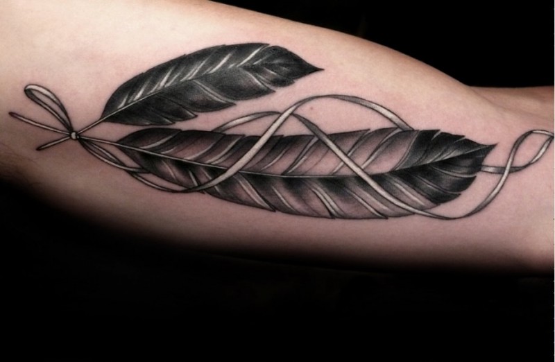 Graue Adlerfedern mit Band Tattoo am Oberarm
