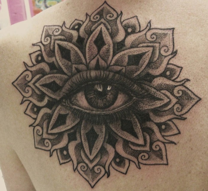 Tatuaje en el hombro, mandala gris oscura con ojo tremendo en el centro