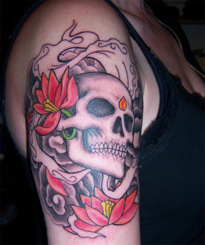 Gray skull with red flowers tattoo on shoulder
