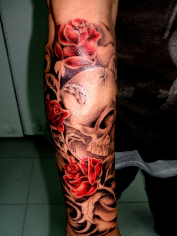 Gray skull with red roses forearm tattoo