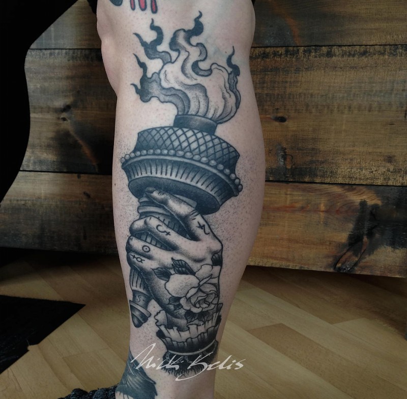 Gray washed style creepy leg tattoo of hand with torch